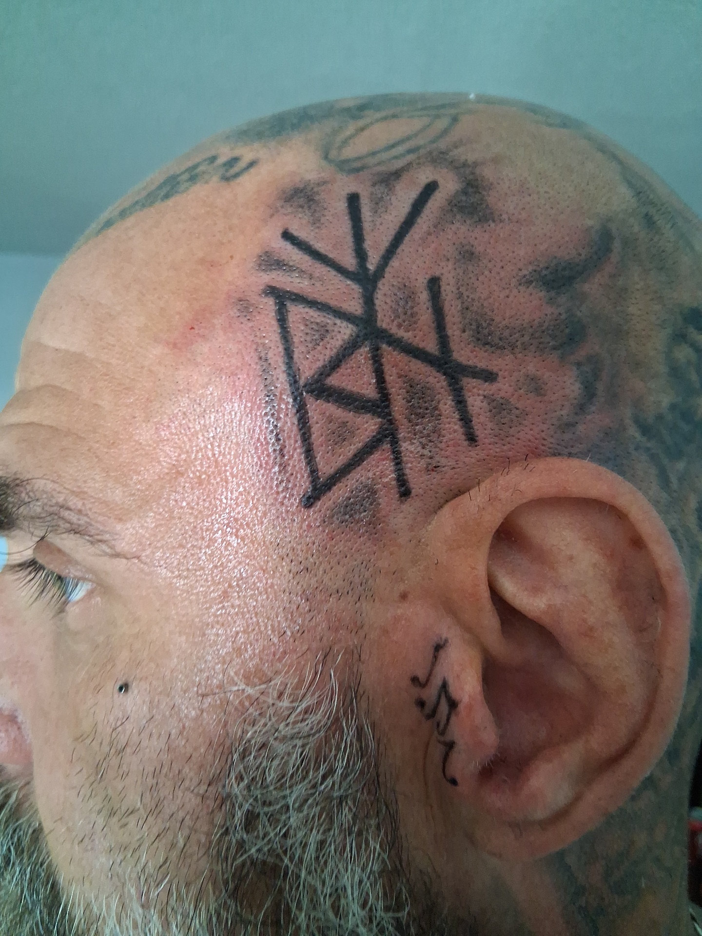 Bold rune / bind-symbol head tattoo, fresh